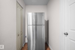 Stainless steel refrigerator with a top freezer, set within a neutral-toned alcove - 