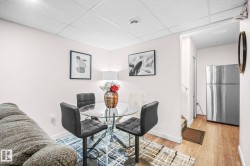 Compact dining area featuring a glass-top table, four counter-height chairs, and wood-finish flooring - 