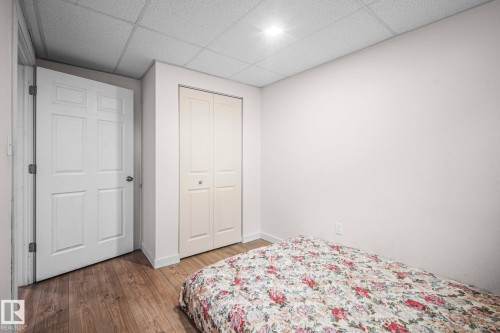 Room featuring wood-finish flooring, white walls, and a drop ceiling with recessed lighting - 4806 117 Ave, Edmonton, AB 