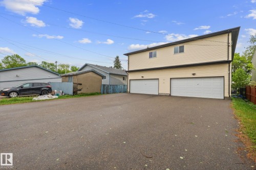 Two-story structure featuring light-colored siding, a dark roofline, and two garage doors - 4806 117 Ave, Edmonton, AB 