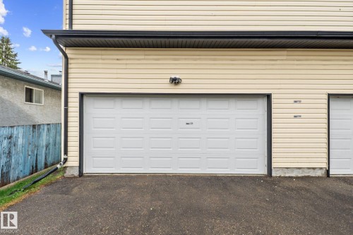 Exterior featuring cream-colored siding, black trim, and a white paneled garage door - 4806 117 Ave, Edmonton, AB 