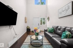 Living space featuring high ceilings, dark wood-finish flooring, and white walls - 