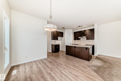 Open-concept living area featuring wood-finish flooring, a contemporary chandelier, and recessed lighting - 18103 77 Street, Edmonton, AB 