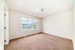 Bright interior space featuring a large window, neutral wall tones, and plush carpet flooring - 