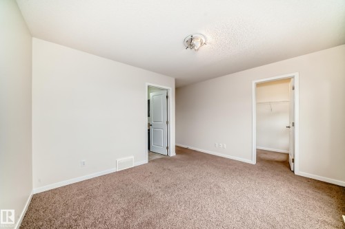 Carpeted room featuring neutral wall tones, white trim, a ceiling-mounted light fixture, and two interior doors - 18103 77 Street, Edmonton, AB 