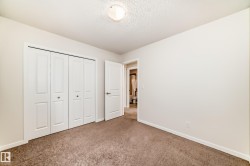 Carpeted room featuring white bi-fold closet doors, a white interior door, and a flush mount ceiling light - 