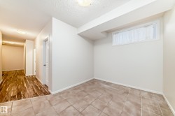 Room featuring light neutral wall paint, a small window with white trim, a textured ceiling, and large square floor tiles - 