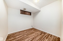 Room featuring wood-finish flooring, white baseboards, and a window with brown drapes - 