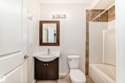 Bathroom featuring a white vanity with integrated sink, dark wood-finish cabinet, and a framed mirror - 
