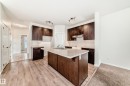 Kitchen featuring an expansive center island with light-toned countertops, dark wood-finish cabinetry, subway tile backsplash, and light wood-finish flooring - 18103 77 Street, Edmonton, AB 