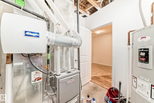 Utility area featuring a water heater, furnace, and exposed ceiling joists - 18103 77 Street, Edmonton, AB 