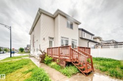 Rear exterior featuring a wooden deck with railing and stairs, vinyl siding, sliding glass doors, and a white privacy fence - 