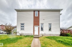 Modern two-story facade featuring white horizontal siding and brown vertical paneling - 
