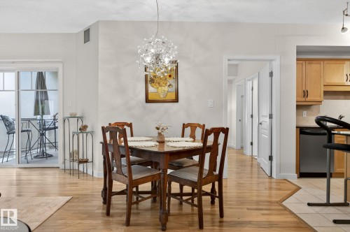Dining area featuring a contemporary chandelier, wood-finish flooring, and direct access to an outdoor patio with sliding glass doors - 208 5 Gate Avenue, St. Albert, AB 