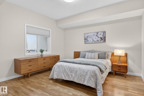 Bedroom featuring wood-finish flooring, a contemporary window with cellular blinds, light-toned walls, and a flat ceiling - 208 5 Gate Avenue, St. Albert, AB 