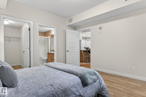 Bedroom with wood-finish flooring, two white panel doors, and neutral wall paint - 208 5 Gate Avenue, St. Albert, AB 