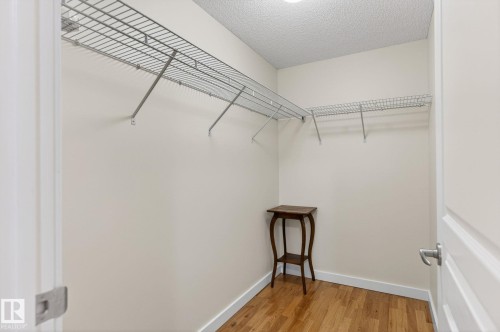 Spacious closet featuring built-in wire shelving, warm wood-finish flooring, and white baseboards - 208 5 Gate Avenue, St. Albert, AB 
