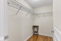 Spacious closet featuring built-in wire shelving, warm wood-finish flooring, and white baseboards - 