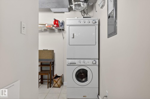Dedicated laundry area featuring a stackable washer and dryer unit, overhead wire shelving, and tiled flooring - 208 5 Gate Avenue, St. Albert, AB 