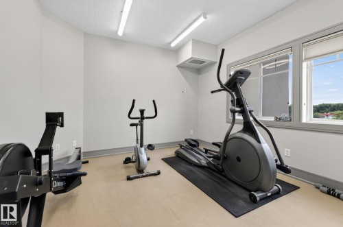 Dedicated fitness space featuring light-colored flooring, neutral wall paint, and two windows providing natural light - 208 5 Gate Avenue, St. Albert, AB 