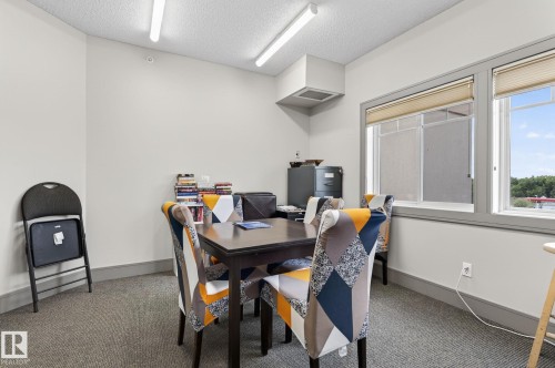 Room with carpeted flooring, white walls, and a drop ceiling with fluorescent lighting - 208 5 Gate Avenue, St. Albert, AB 
