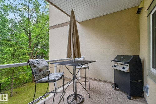 Covered balcony featuring a textured stucco exterior, white soffit, and railing - 208 5 Gate Avenue, St. Albert, AB 