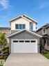 Modern two-story residence featuring a stone veneer garage facade and a white paneled garage door with window inserts - 3150 Magpie Way, Edmonton, AB 