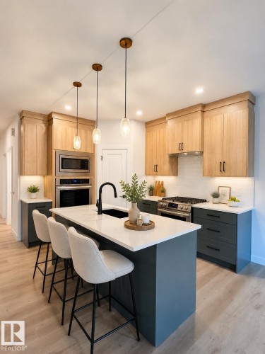 Contemporary kitchen featuring a large central island with seating, white countertops, and a black sink with a matte black faucet - 3150 Magpie Way, Edmonton, AB 