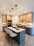 Contemporary kitchen featuring a large central island with seating, white countertops, and a black sink with a matte black faucet - 3150 Magpie Way, Edmonton, AB 