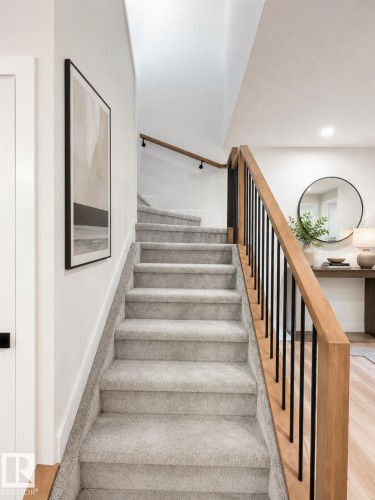 Carpeted staircase featuring a light wood handrail and black metal balusters - 3150 Magpie Way, Edmonton, AB 