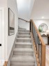Carpeted staircase featuring a light wood handrail and black metal balusters - 3150 Magpie Way, Edmonton, AB 