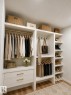 Custom built-in closet system featuring multiple hanging rods, shelving, drawers with gold-finish hardware, and dedicated shoe storage - 3150 Magpie Way, Edmonton, AB 