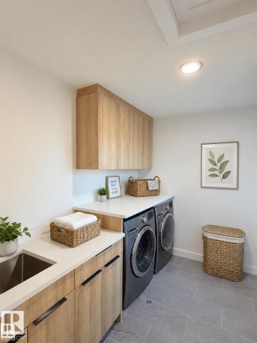 Laundry room featuring a stainless steel sink, wood-finish cabinetry, light-toned countertops, and gray tile flooring - 3150 Magpie Way, Edmonton, AB 