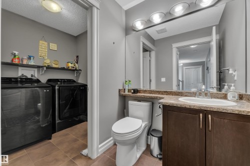 Functional bathroom featuring a single vanity with an integrated sink, a large mirror, and overhead strip lighting - 6116 11 Avenue, Edmonton, AB 