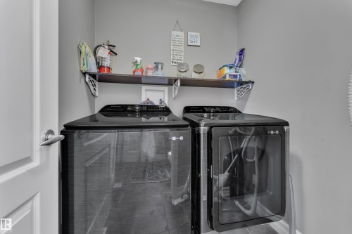 Dedicated laundry area featuring a dark wood-finish wall shelf, contemporary gray wall paint, and durable tile flooring - 6116 11 Avenue, Edmonton, AB 