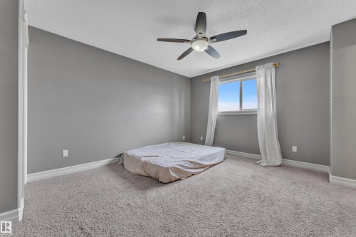 Carpeted interior space featuring a window with white trim, a ceiling fan with brushed nickel accents, and neutral gray wall tones - 6116 11 Avenue, Edmonton, AB 