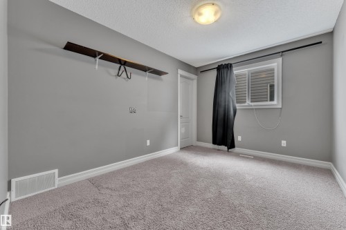 Spacious room featuring plush gray carpeting, neutral gray walls, and white trim - 6116 11 Avenue, Edmonton, AB 