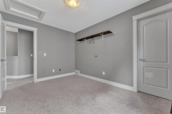 Neutral-toned room featuring a light gray carpet, matching wall paint, and white trim - 