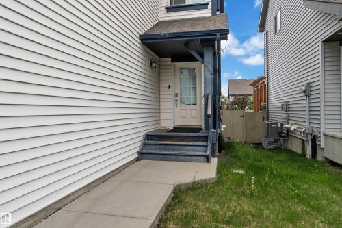 Entryway featuring a white paneled door, sheltered by a dark-colored overhang, and accessible via dark-stained steps - 6116 11 Avenue, Edmonton, AB 