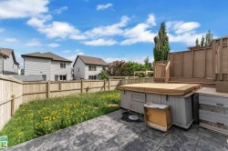 Backyard featuring an imprinted concrete patio, a wooden privacy fence, a raised wood deck, and a hot tub - 