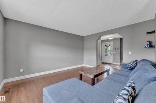Open living area featuring wood-finish flooring, light grey walls, and white baseboards - 6116 11 Avenue, Edmonton, AB 