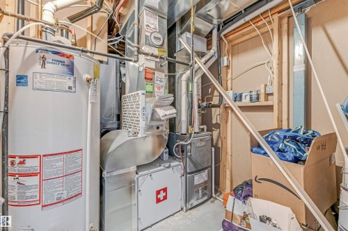 Water heater and furnace units featuring visible ductwork and piping - 5928 12 Avenue, Edmonton, AB 