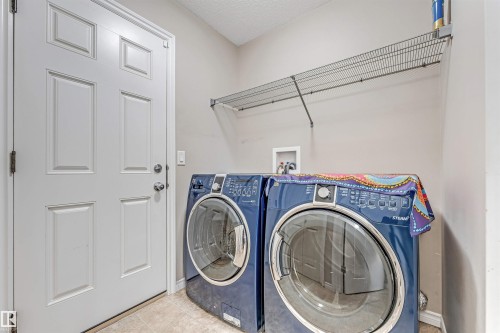 Dedicated laundry area featuring a white paneled door, light-toned wall paint, and overhead wire shelving - 5928 12 Avenue, Edmonton, AB 