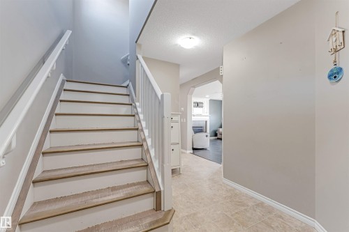 Staircase with white risers and wood-finish treads, featuring a white handrail and balusters - 5928 12 Avenue, Edmonton, AB 