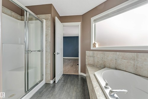 Corner soaking tub with light-toned tile surround and chrome fixtures - 5928 12 Avenue, Edmonton, AB 
