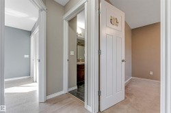 Hallway with light wood-finish flooring, white baseboards, and neutral wall paint - 