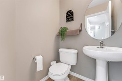 Pedestal sink with chrome faucet hardware, round wall mirror, and neutral wall tones - 