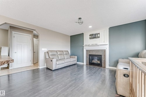 Living area featuring a fireplace with a mantel, tile surround, and white trim - 5928 12 Avenue, Edmonton, AB 