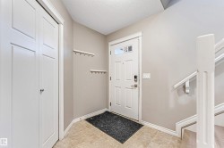 Entryway featuring neutral wall tones, ceramic tile flooring, a paneled front door with decorative glass inserts, and a built-in closet with bi-fold doors - 