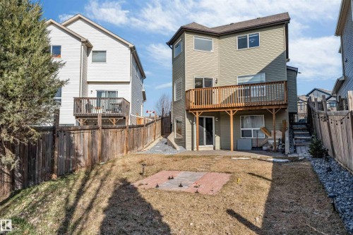 Expansive backyard featuring a multi-level wooden deck, ground-level patio access, and a paved brick area - 5928 12 Avenue, Edmonton, AB 